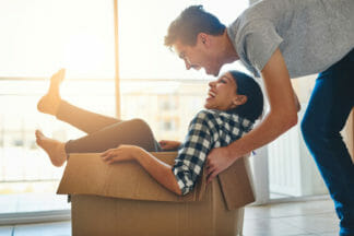 A man and woman are sitting in a cardboard box.