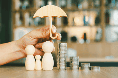 Wooden figures under an umbrella next to a stack of coins, symbolizing how to start saving money and build a financial safety net